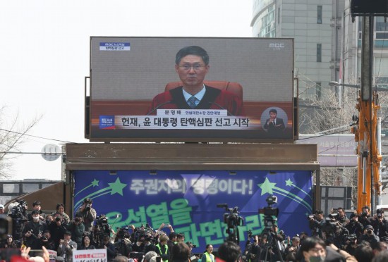  4月4日，民众在韩国首都首尔的韩国宪法法院附近观看尹锡悦弹劾案宣判过程的电视直播。新华社记者姚琪琳摄