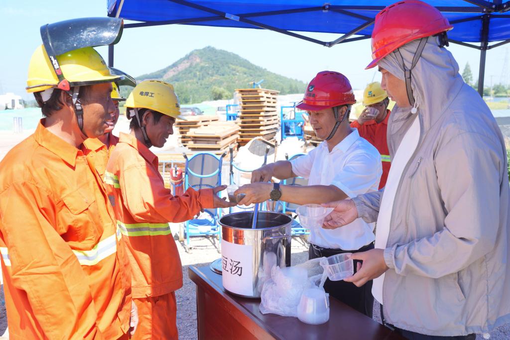 7月3日,在浙江省绍兴市上虞区长塘镇,104国道改建工程上虞段的建筑工人在工地领绿豆汤解暑。(新华社记者 翁忻旸 摄)